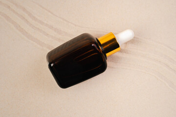 Essence for the health of facial skin. Mockup for your product. The collagen hydrating serum lies on the sand.