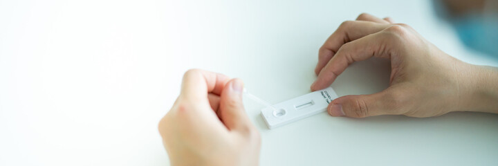 Asian young woman using SARS 2019-nCoV COVID-19 coronavirus antigen rapid test kit - ag test kit at home. 