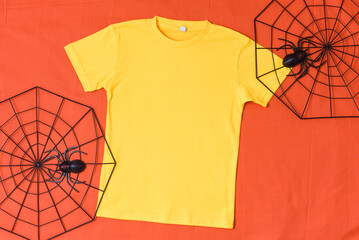 Yellow t-shirt mockup with halloween spiderweb decor on orange halloween background