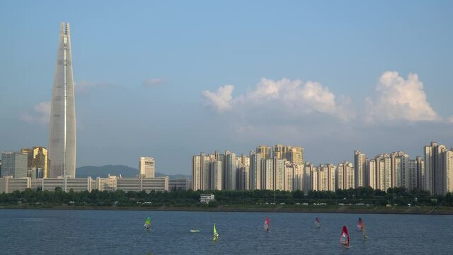 A Group of men is windsurfing at Han river near Lotter tower daytime, Jamsil district of Seoul city, South Korea. People  sail of windsurf boards in Summer