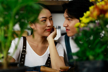 Young asian couple wearing jean overall and white t-shirt doing gardening and growing small plants and trees. Concept home garden hobby
