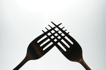 Two shiny metal forks on a white background.