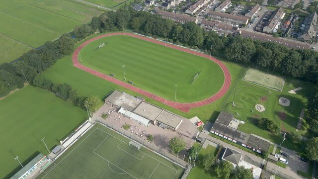Cinematic aerial of running track on green sports field