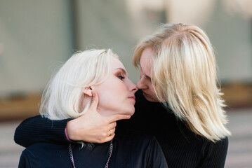 Two young females walking smiling embracing and kissing outdoor in the city