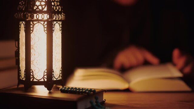 Asian Muslim woman reading the Quran and appreciates and faith The Holy Al Quran with written Arabic calligraphy meaning of Al Quran, Arabic word translation: The Holy Al Quran.