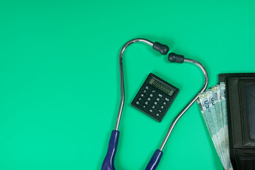 Medical and business concept. Layout of stethoscope, calculator and wallet with cash reference to medical bills. Selective focus points