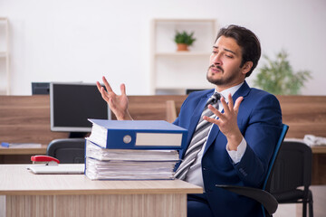 Young male employee and too much work in the office