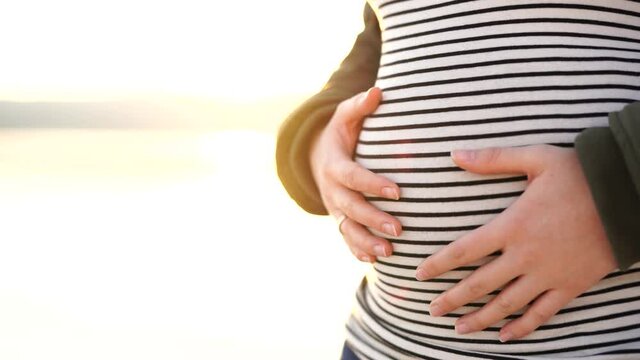 Girl stroke a pregnant tummy with her hands 