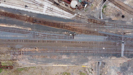 top down drone view of  long crossing vintage railway tracks, sheds and carriages