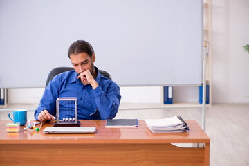 Young male teacher physicist sitting in the classroom