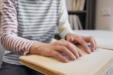 Close up of unrecognizable person reading Braille book in college library, copy space