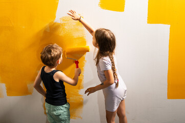 A boy and a girl paints a wall at home in yellow