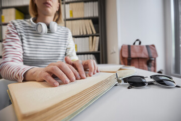 Close up of young blind woman reading Braille book in college library, copy space