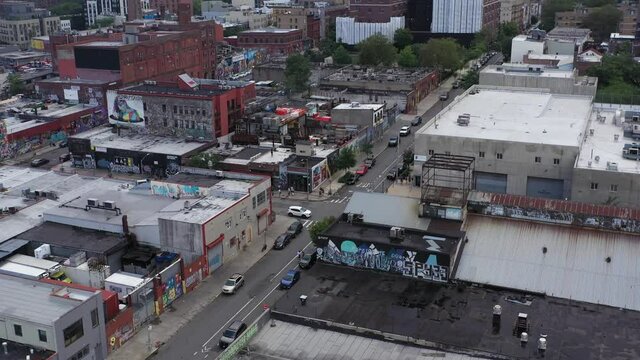 Slow aerial tilt up over Brooklyn industrial rooftops looking toward Manhattan skyline on a rainy day