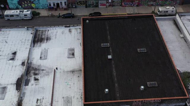 Aerial flight looking down and slight tilt up over Brooklyn warehouse rooftops, very urban industrial