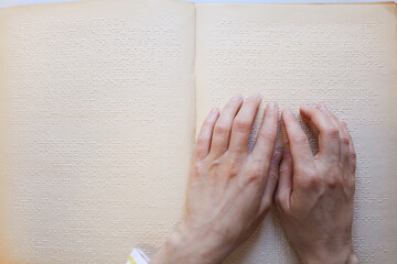Top view closeup of unrecognizable blind person reading Braille book, copy space