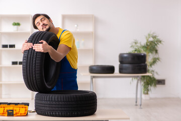 Young male garage worker with tyre at workshop © Elnur