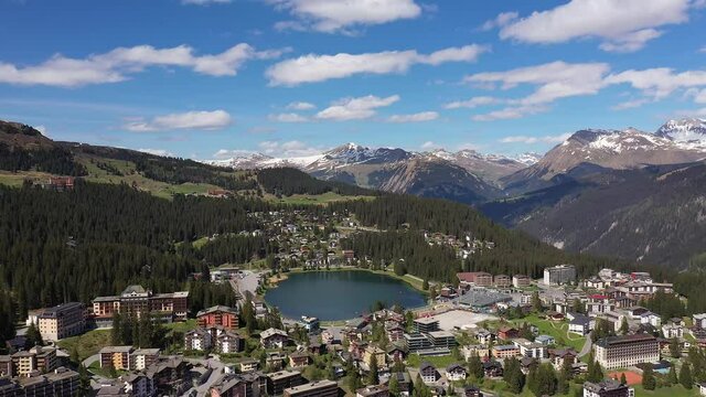 Aerial drone footage of the Arosa ski resort and village in Spring in Canton Graubunden in the alps in Switzerland. Shot with a rotation motion