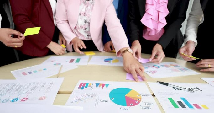Group of businesswomen meeting together brainstorming at working desk. They give each idea and decision in memo note on desk with self-confidence.