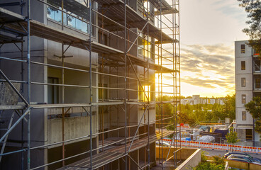Construction site in sun rise behind the building and metal scaffoldings 