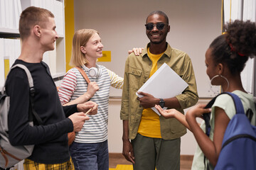 Waist up portrait of diverse group of students chatting with smiling blind man - obrazy, fototapety, plakaty
