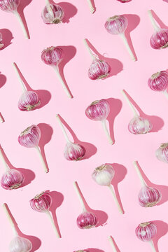 Bulbs of garlic on a colored background, colorful garlic  pattern. Garlic pattern on pink background