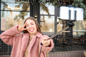 Beautiful young woman taking selfie outdoors