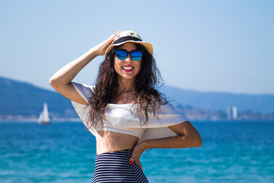 Woman On The Beach Putting On Her Hat