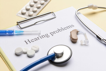 Clipboard with text HEARING PROBLEMS and pills on color background
