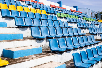 Empty old blue seats in the blue,yellow green and red in stadium.