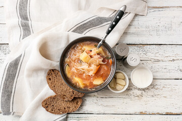Composition with tasty sauerkraut soup on light wooden background