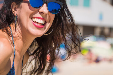 Portrait of smiling woman with sunglasses in bikini on the beach