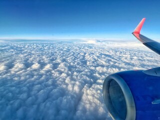 A passenger plane flies over the clouds at dawn. The view from the plane window on the white clouds and the wing. Flying in the sky.  