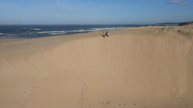Woman and her son sitting on edge of dune