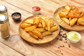 Plates with tasty baked potato and sauce on wooden background