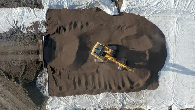 Aerial view of work in a road construction site. Excavator and construction worker doing their job.