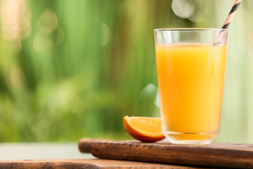 Fototapeta premium Board with glass of tasty orange juice on table outdoors