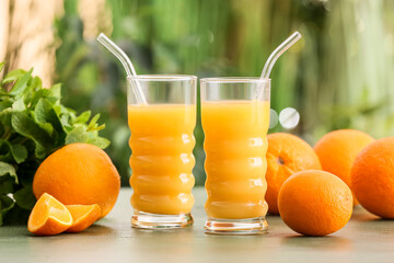 Glasses of tasty orange juice on table outdoors