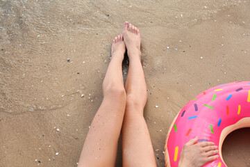 Beautiful young woman with inflatable ring on sea beach