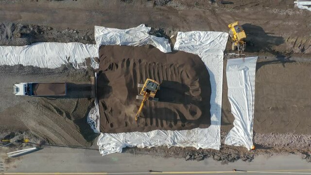 Heavy equipment work at a road construction site. Aerial top-down view. Excavator and Dump Truck.