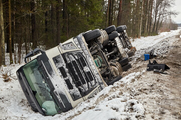 Car accident on the slippery road in winter. The truck rolled over on its side