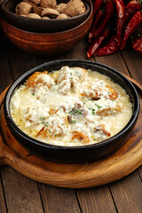 Georgian chkmeruli chicken dish with cream sauce on a wooden background