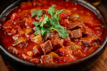 Georgian veal chashushuli stew with tomatoes on a wooden background