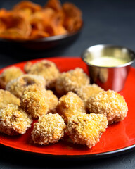 Deep fried cheese balls served in a red plate with sauce over black background. Isolated on white.