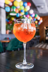 Red cocktail with ice in a tall wine glass. Served on a table in restaurant or bar