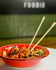 Buckwheat noodles with chicken and vegetables in Japanese style, served in a red bowl in restaurant