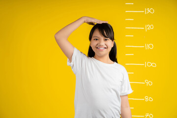 Little girl measuring her height on color background.