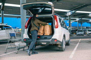 woman put bags with products in car trunk after grocery store