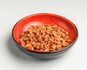 Spicy bombay peanuts in a small red bowl over white background.