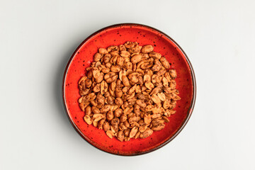 Spicy bombay peanuts in a small red bowl over white background.